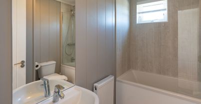Internal of a cabin bathroom with shower over bath, toilet and sink