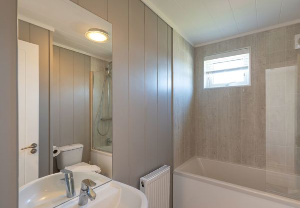 Internal of a cabin bathroom with shower over bath, toilet and sink