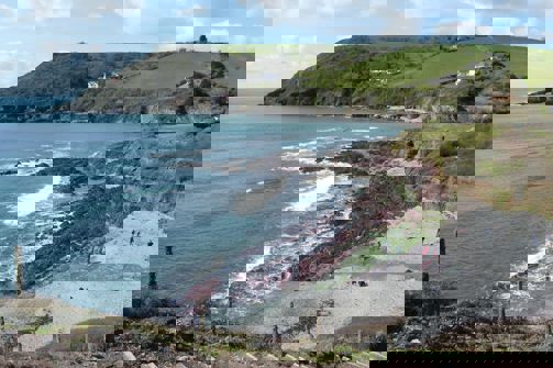 A small rocky bay at the bottom of rolling countryside hills