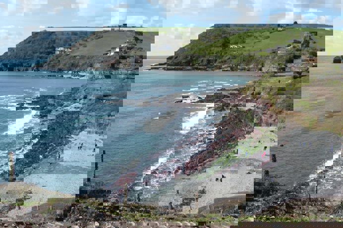 A small rocky bay at the bottom of rolling countryside hills