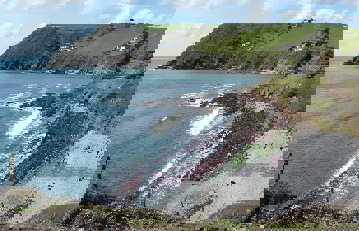 A small rocky bay at the bottom of rolling countryside hills