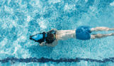 A young boy underwater in an outdoor pool on an aqua jet 