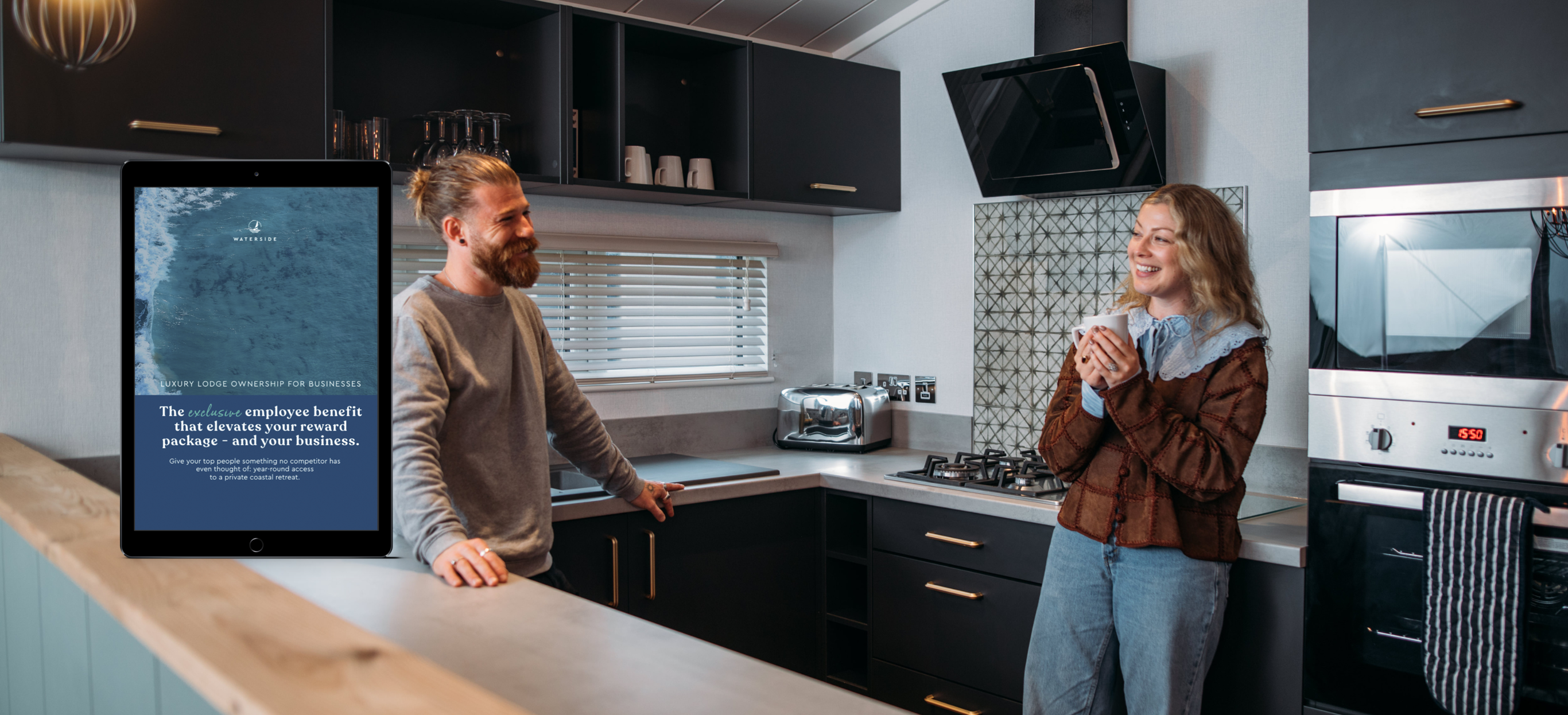 A couple in the kitchen of a lodge smiling at each other with a mockup of an ownership guide overlaid in the corner
