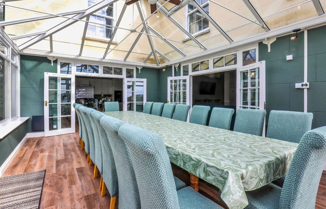 Internal of a manor house conservatory dining area with table and chairs for 18 guests