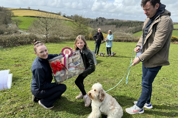 A child being presented an award for their dog at Trufts dog show at the agility course at Tregoad Holiday Park. The dog and another older man and the woman presenting the award are also in shot