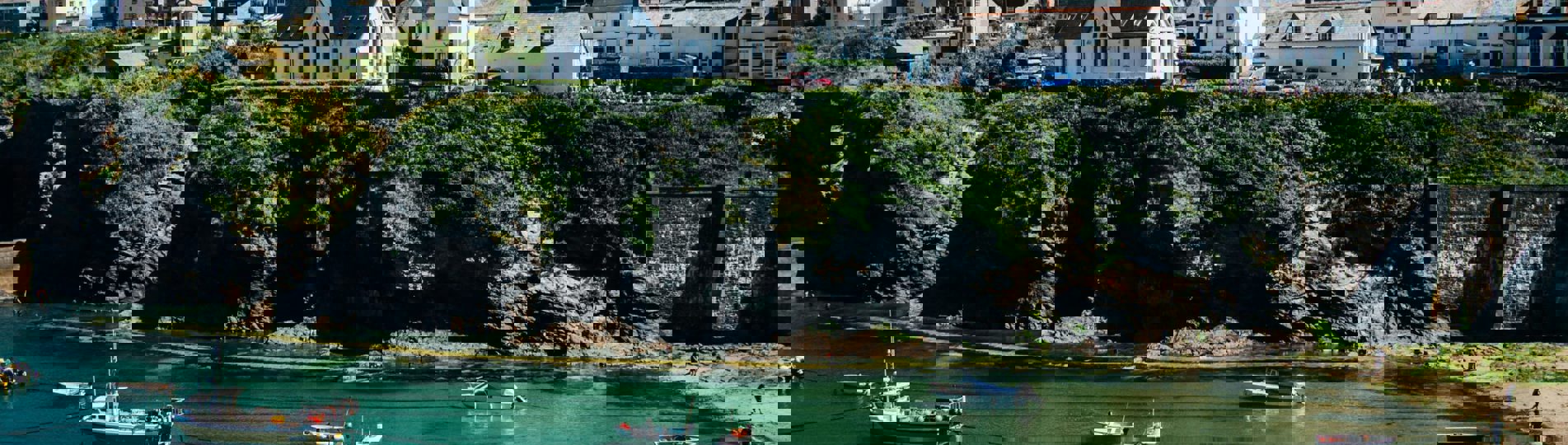 A quiet Cornwall cove with boats in the water and houses on the hill