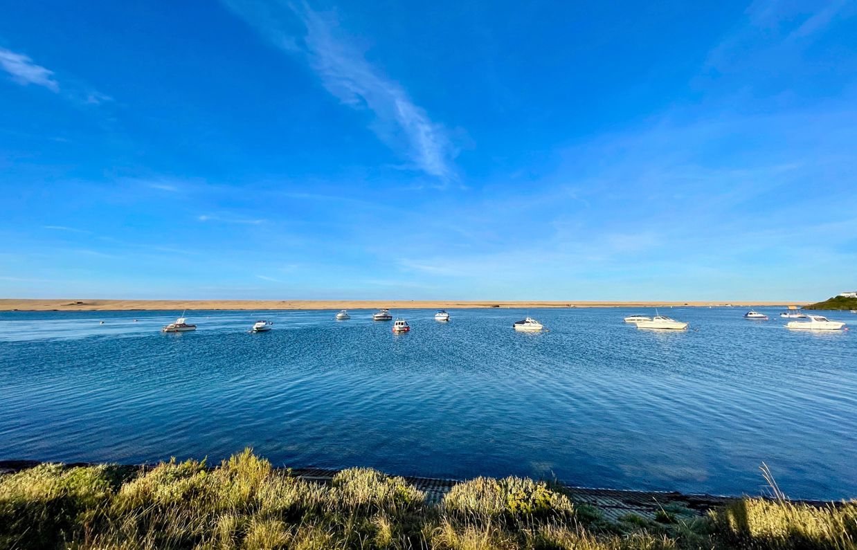 A range of boats on the sea with Chesil Beach in the background
