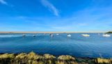 A range of boats on the sea with Chesil Beach in the background