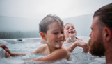 Two young boys playing in a hot tub with their dad on a cloudy day