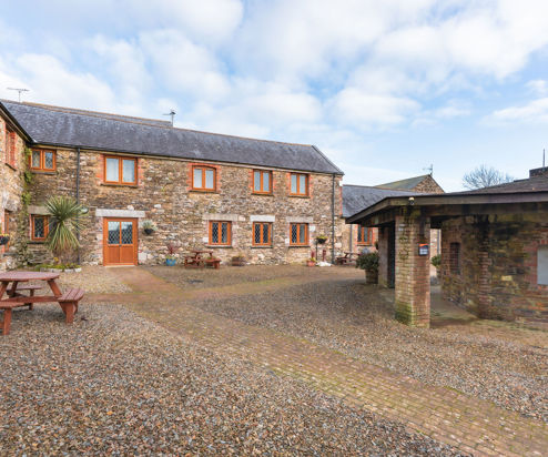 External of a cottage courtyard area with outdoor benches and flowers