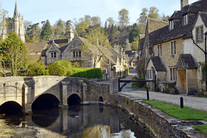 A small village with a bridge over a river, a church and quaint cottages