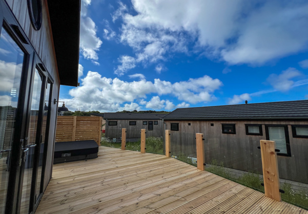 External of a luxury lodge on pitch with decking and hot tub
