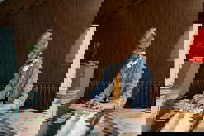 A young man wearing glasses, a shirt and tie sat at a desk on the phone