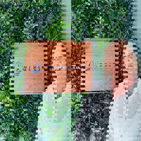 A lady wearing smart clothing smiling next to the Waterside sign