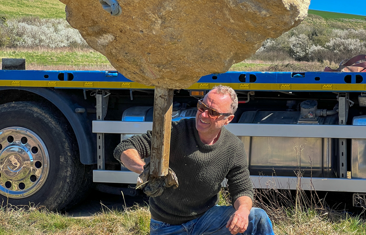 Installation of a stone sculpture in a field with blue skies