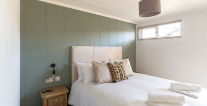 Double bedroom with sage green feature wall and comfy furnishings