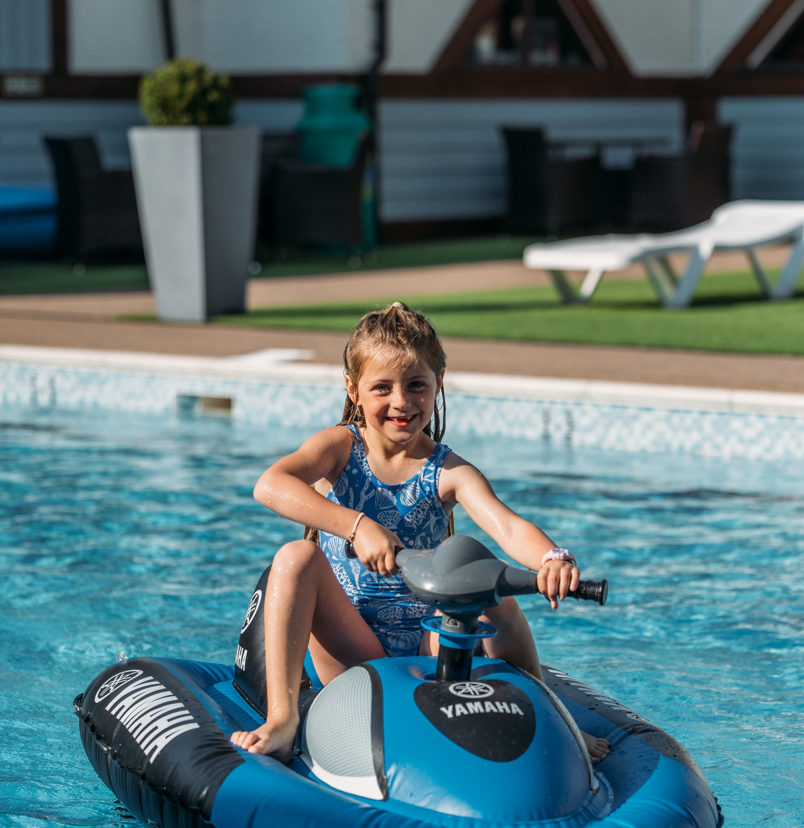 A young girl on a mini jet ski on an outdoor swimming pool