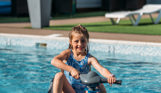 A young girl on a mini jet ski on an outdoor swimming pool