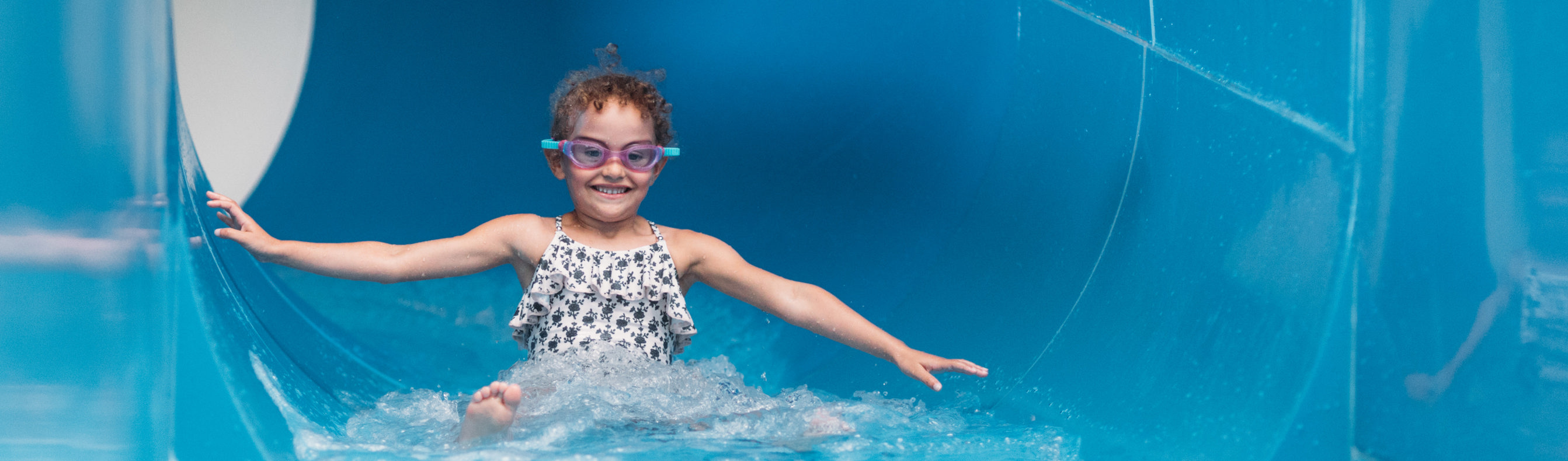 Child smiling as she comes to the end of a water slide