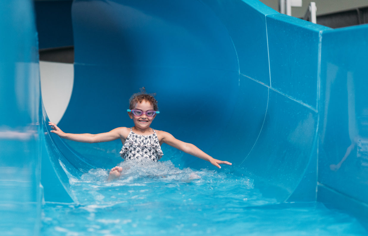 Child smiling as she comes to the end of a water slide