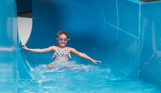 Child smiling as she comes to the end of a water slide