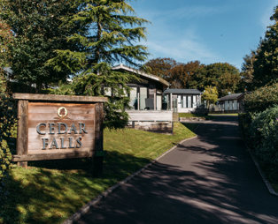 Cedar Falls entrance sign on Osmington Mills Lodge Park surrounded by lodges and woodland
