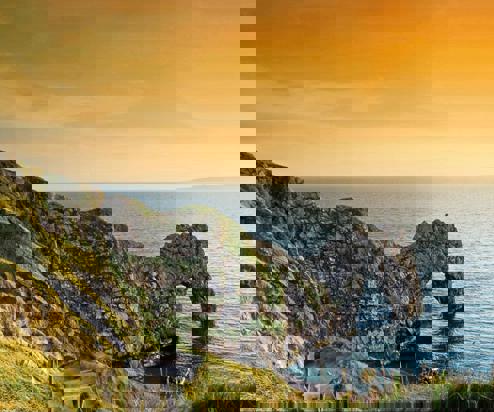 A limestone arch along the coastpath at sunrise