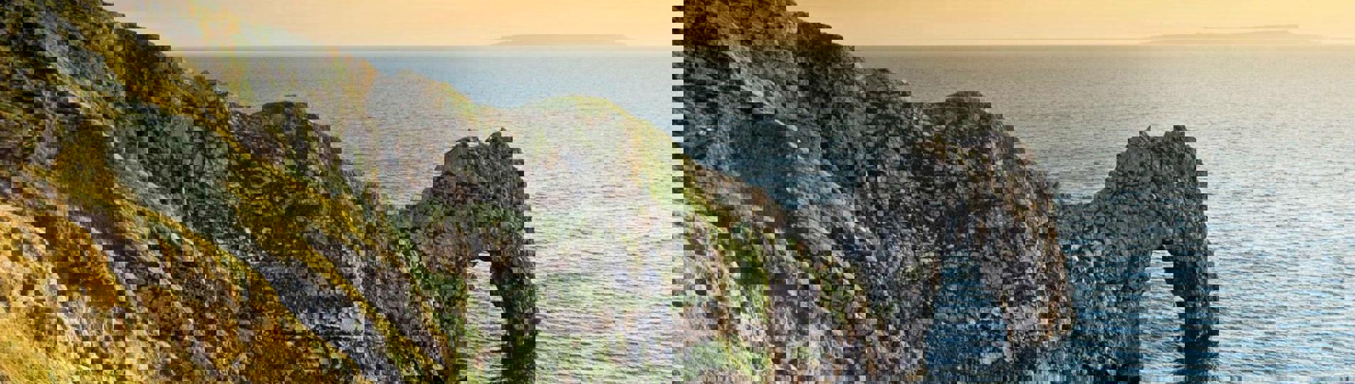 A limestone arch along the coastpath at sunrise