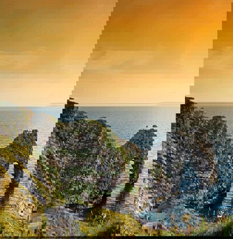 A limestone arch along the coastpath at sunrise