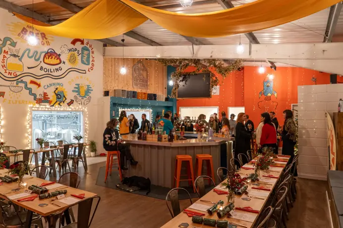 A brewery taproom with tables and chairs and people gathered