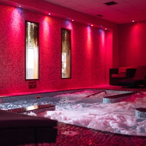 A hydrotherapy pool with loungers and calm lights