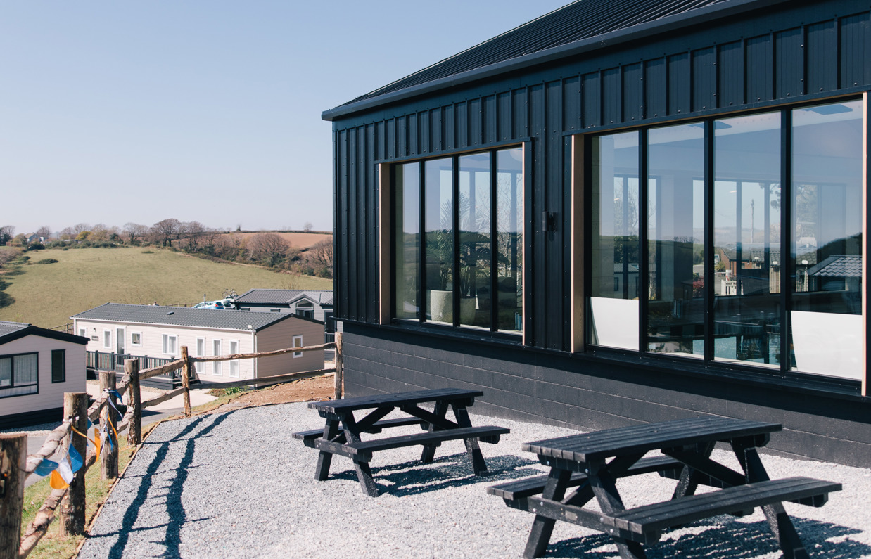 The external of an indoor heated swimming pool within a barn style building with boho-chic styling and countryside views