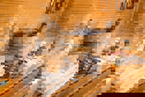 The inside of a sauna with towels, products, steam and tea lights