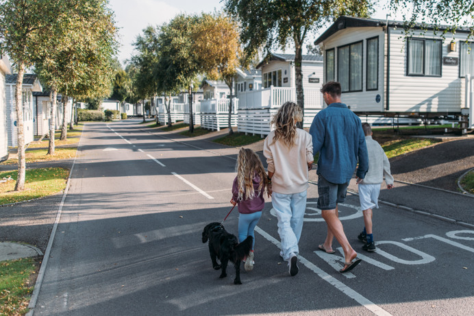 Family walking dog down a tidy lane surrounded by caravans