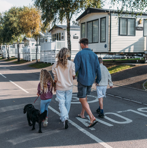 Family walking dog down a tidy lane surrounded by caravans