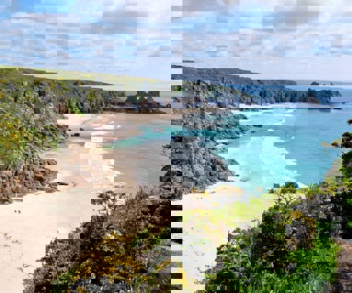 A sandy beach at low tide with blue waters
