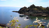Polperro coast path looking towards the sea with boats on a sunny, blue sky day