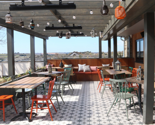 An outdoor seating area at Stargazy with a veranda, benches, tables and chairs and countryside views
