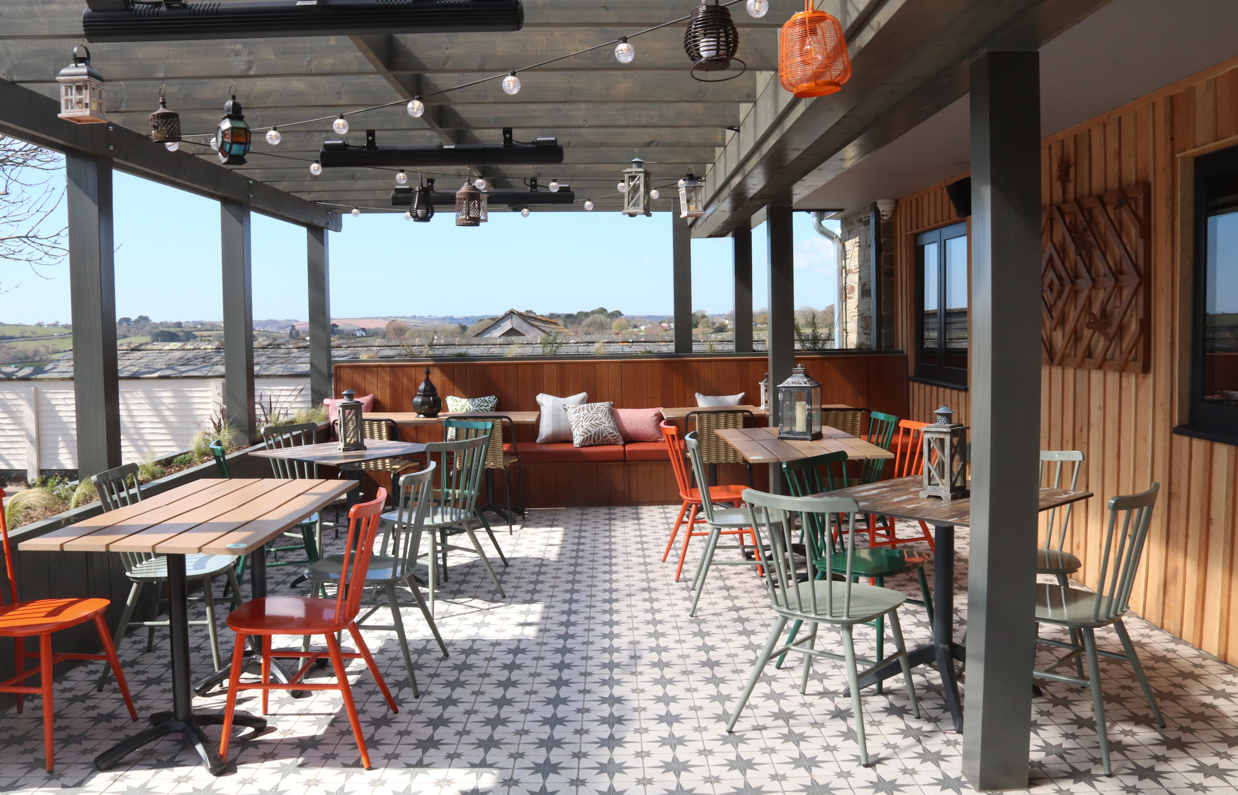 An outdoor seating area at Stargazy with a veranda, benches, tables and chairs and countryside views