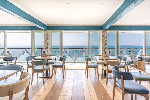 Striking sea views from the inside of Drift Bar & Grill seating area on a sunny, blue sky day