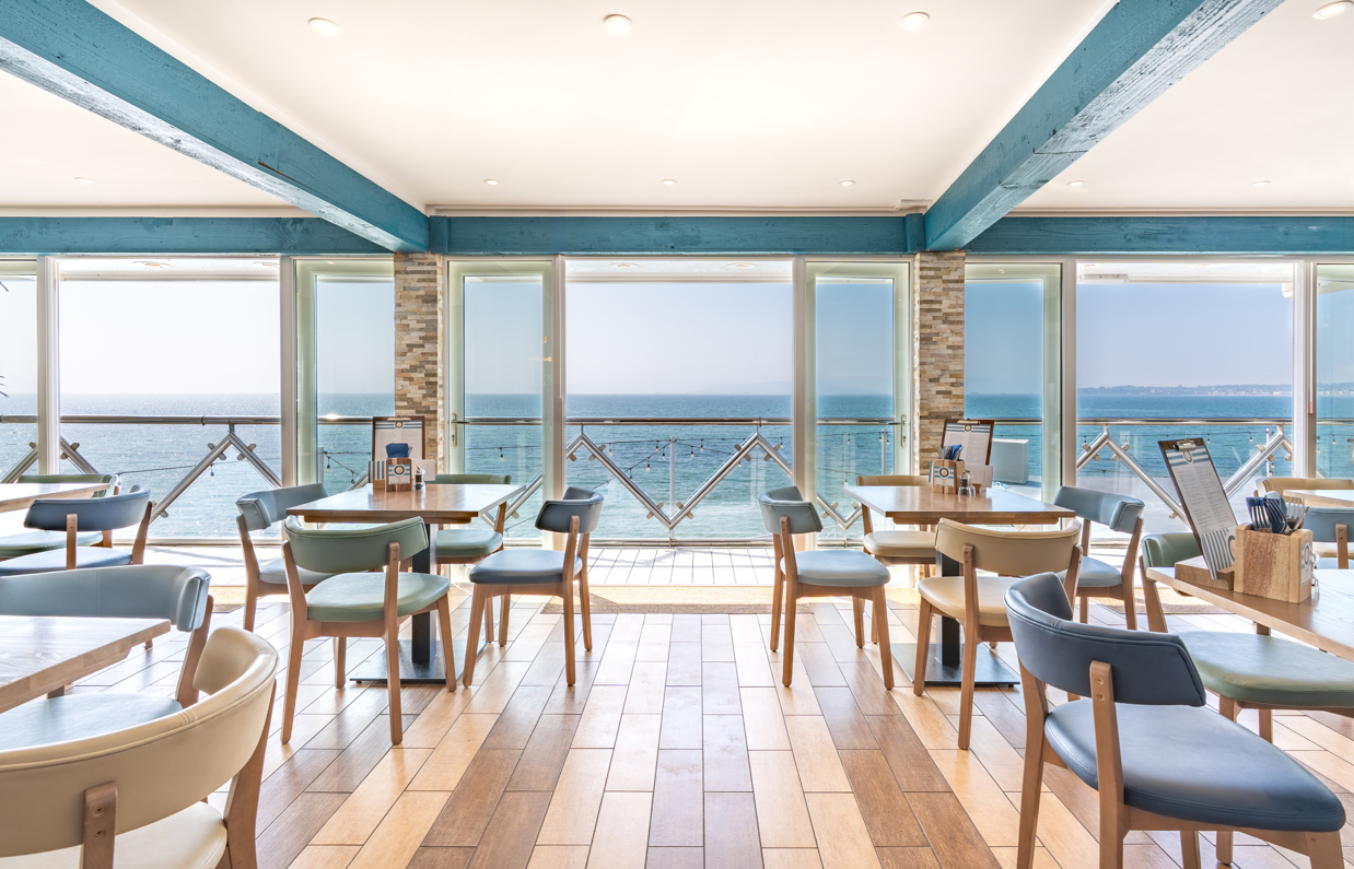 Striking sea views from the inside of Drift Bar & Grill seating area on a sunny, blue sky day