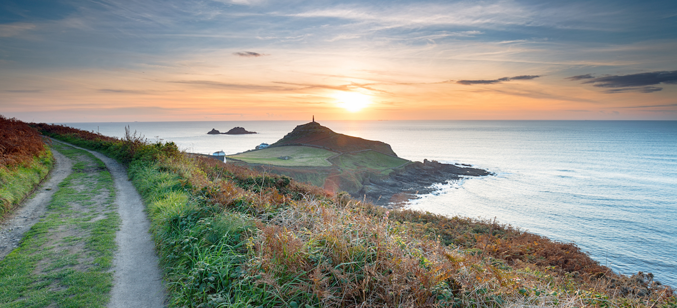A coastal path with views of the sea and sunset