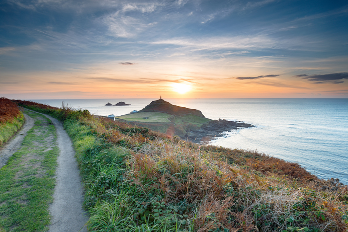A coastal path with views of the sea and sunset