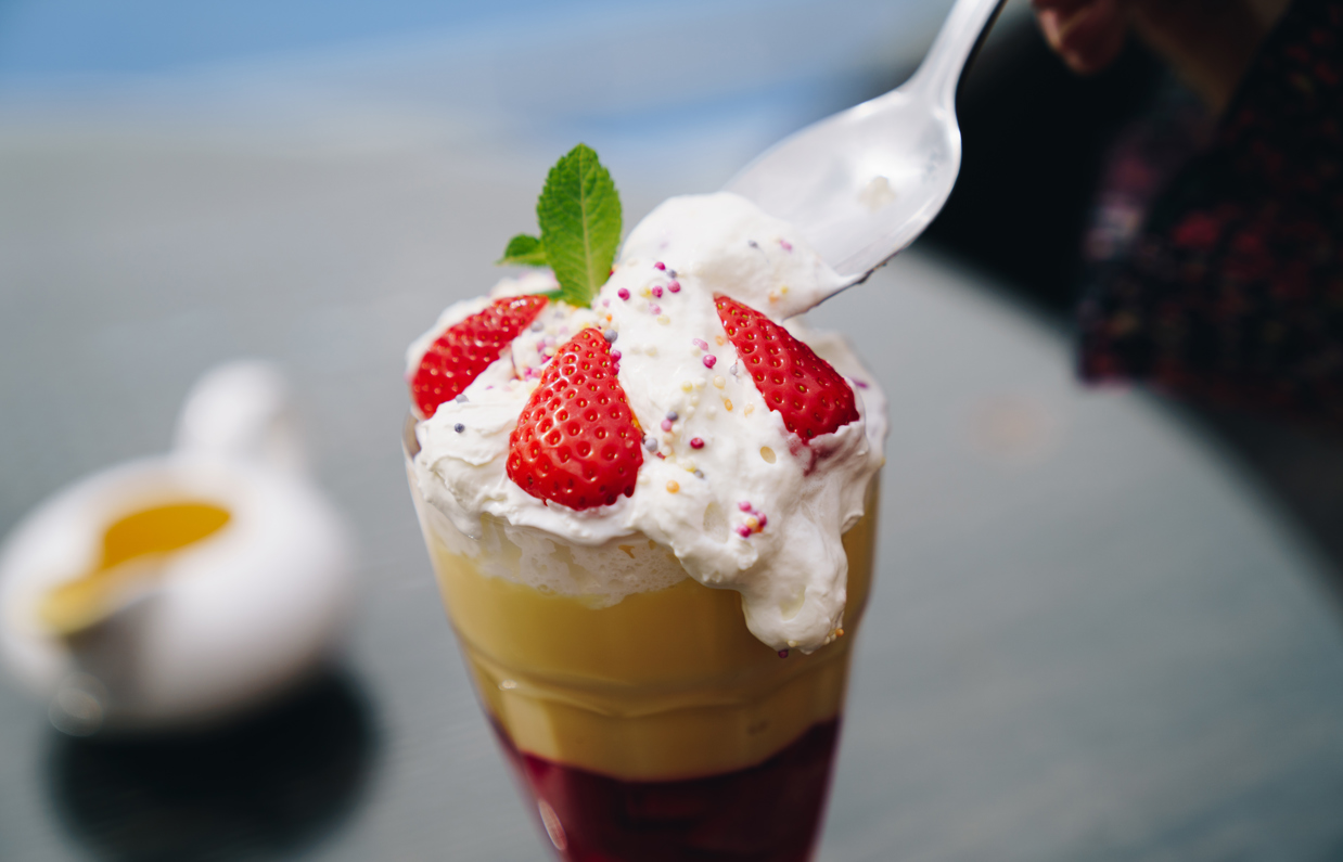 An ice cream sundae having a scoop taken out of it with a spoon