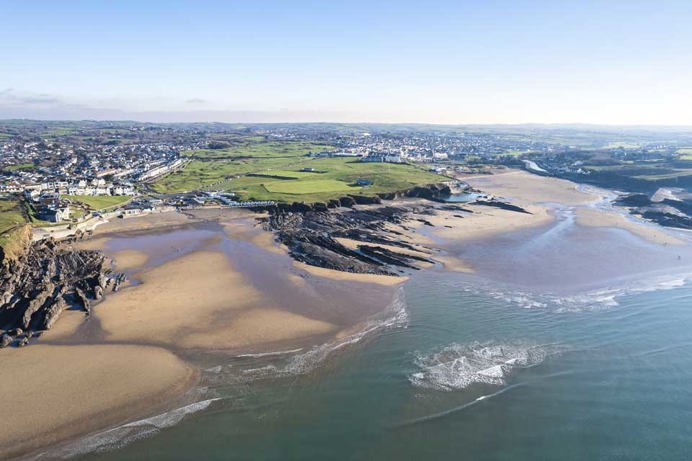 A sandy beach with rocky headland and nearby towns