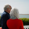 A couple on the balcony of a caravan looking out to the sea and Chesil Beach