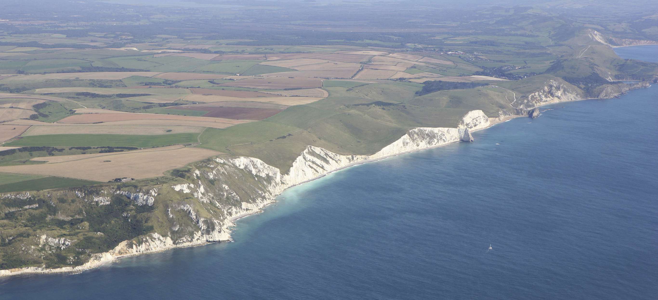 Aerial view of a stretch of the Jurassic Coast including blue sea, rugged cliffs and countryside