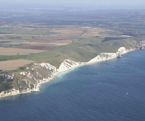 Aerial view of a stretch of the Jurassic Coast including blue sea, rugged cliffs and countryside