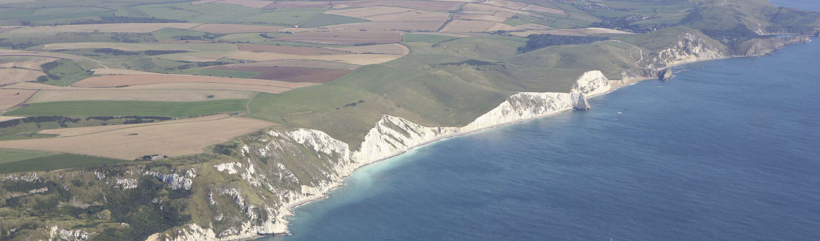Aerial view of a stretch of the Jurassic Coast including blue sea, rugged cliffs and countryside