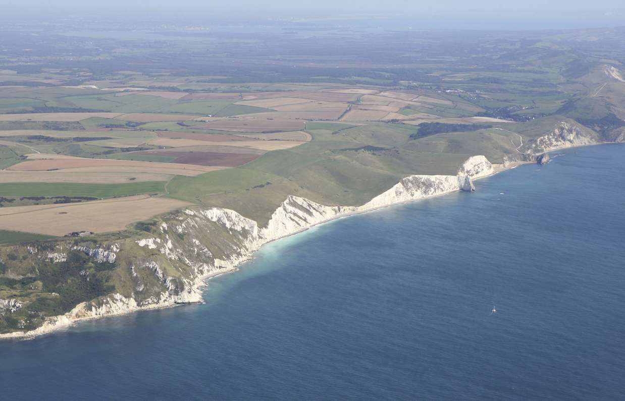 Aerial view of a stretch of the Jurassic Coast including blue sea, rugged cliffs and countryside